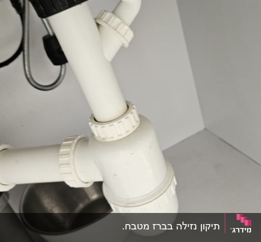 צינורות פלסטיק לבנים מתחת לכיור מטבח